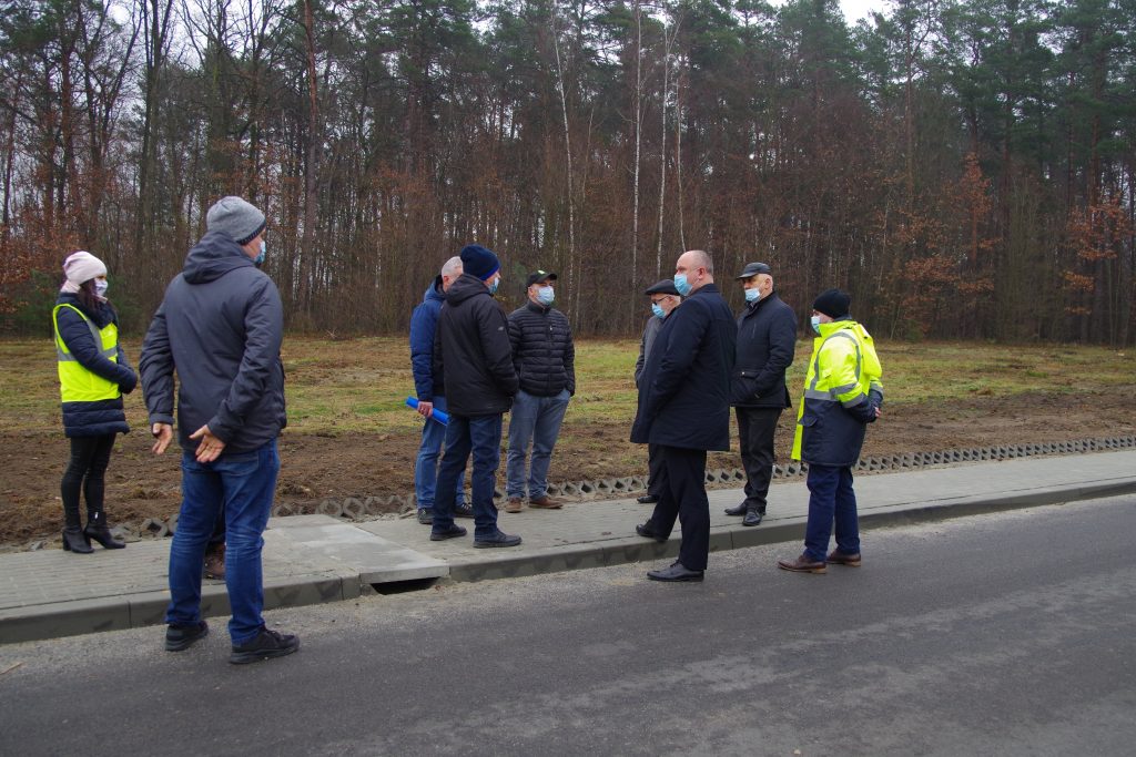 Przedstawiciele powiatu leżajskiego oraz wykonawcy stoją na chodniku poprowadzonym wzdłuż nowej drogi.