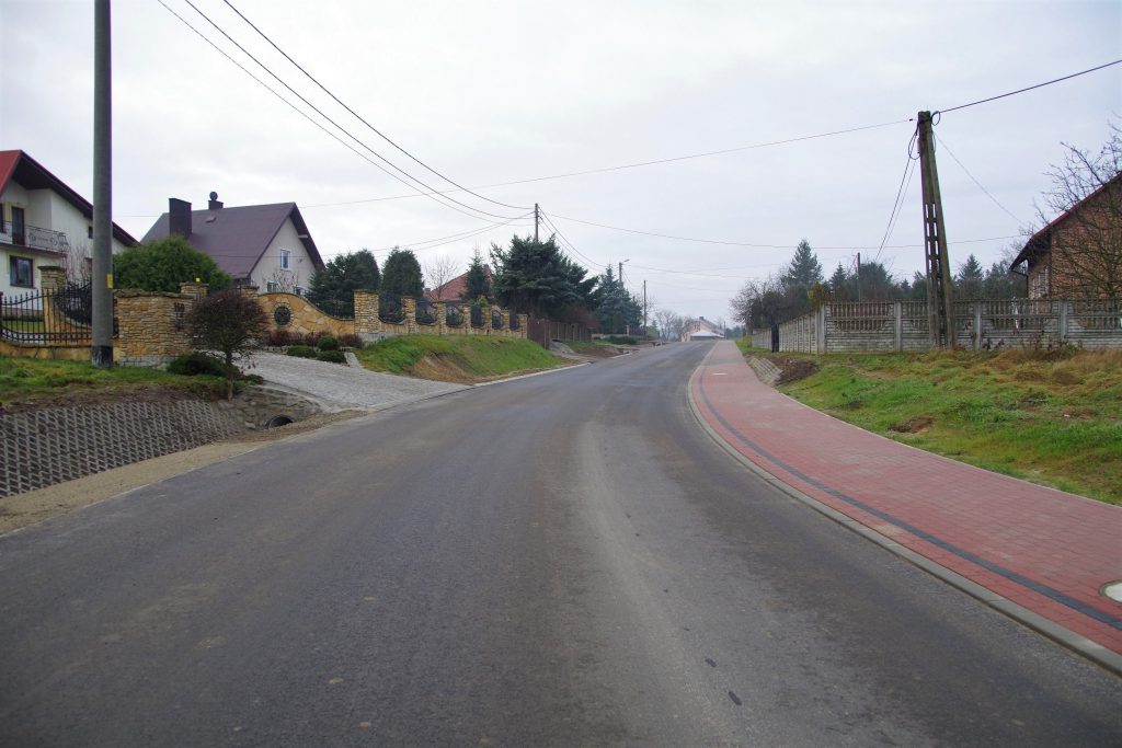 Fragment przebudowanej drogi w środku wsi Wólka Grodziska. Po prawej stronie znajduje się chodnik.