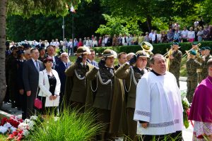 Uczestnicy uroczystości stojący na placu.