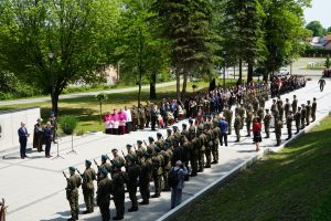 Żołnierze stojący w dwóch szeregach, uczestnicy uroczystości zwróceni twarzą do pomnika i osoby przemawiającej przed nim.
