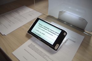 Lupa elektroniczna umieszczona na dokumentach leżących na biurku.